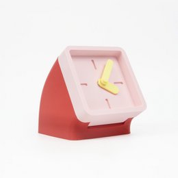  Cranberry red and pastel peach table clock with a modern, minimalist design. Features a square shape, contrasting colors, and a simple analog clock face.