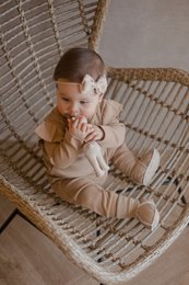 Beige sheepskin-lined baby slippers with soft, cozy material and comfortable fit for infants.
