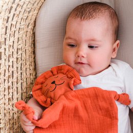  Organic cotton lion doudou, a soft and cuddly comfort cloth in a warm orange color with a cute lion design, perfect for babies and toddlers.