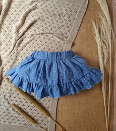 A white long-sleeved top with a ruffled blue skirt, suitable for a young girl. The outfit includes a blue bow accessory.