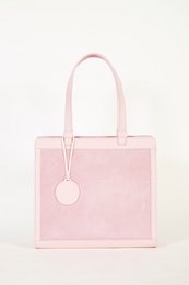  A pink square-shaped handbag with a circular charm and two handles.