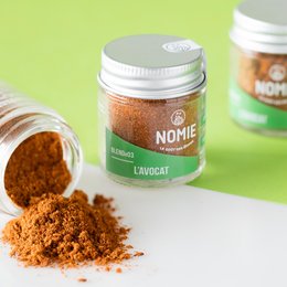 Avocado seasoning in a glass jar with a white lid. The seasoning appears to be a reddish-orange powder.