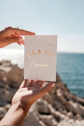Elegant gold-foil love card with scenic ocean backdrop.