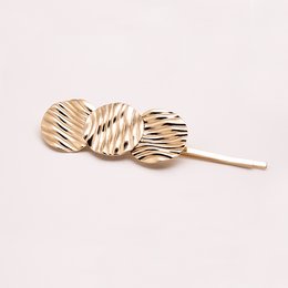 Wavy hair clip made of beige and brown striped material, with a curved shape and a metal clip for securing hair.