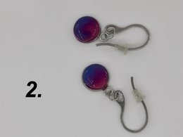  A set of three demi gender pride necklaces with circular pendants in pastel colors on a silver chain.