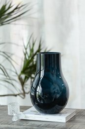 Deep blue glass vase with elegant modern design, suitable for displaying flowers or decorative elements.
