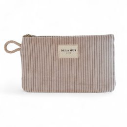  Beige striped makeup pouch with "De la Mer" branding, suitable for storing and organizing cosmetics and personal care items.