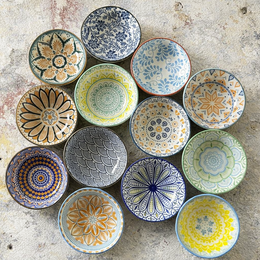  Decorative ceramic bowls in assorted colors and patterns, including round, shallow bowls with intricate designs in blue, yellow, red, and green.
