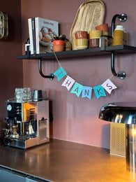 Decorative party bunting with "Growing Garland Thanks" text and a hanging tag. The garland features a rustic, natural style with a variety of colorful decorative elements.