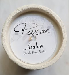 Tall, round, white scented candle with the name "Azhar" written on the label in cursive script.