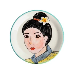 Decorative ceramic plate featuring a portrait of a woman with a flower in her hair. The plate has a round shape and a turquoise border. The woman has dark hair and is wearing a blue shirt.