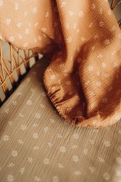  Beige daisy-patterned fitted bassinet sheet, made of soft, breathable material.