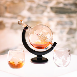 Elegant glass decanter and glasses set with a globe design, perfect for serving whisky or other spirits.