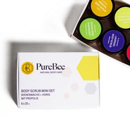 A set of colorful body scrub mini jars in a gift box. The jars feature various scents and ingredients like lavender, lemon, and propolis.