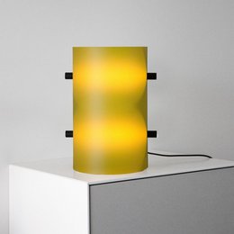  A tall, cylindrical table lamp with a lemon yellow glass shade. The lamp has a modern, minimalist design and is suitable for use as a decorative lighting piece in a living room or bedroom.