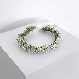 A white floral wreath made of dried daisies, suitable for wearing as a hair accessory.