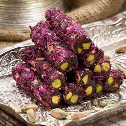 A vibrant, chewy gummy candy made with rose-flavored fruit and crunchy pistachios. The deep pink color and flecks of green pistachio create an eye-catching, artisanal appearance.