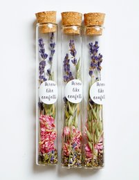 Dried flower seeds in a glass bottle with cork stopper, containing lavender and other dried flowers. Suitable for planting or decorative use.
