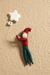 Decorative wand with red and green felt figure and star-shaped ornaments.