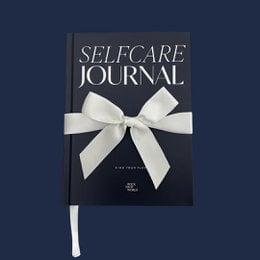 A red hardcover journal titled "The Selfcare Journal 2025" for daily planning and organization.