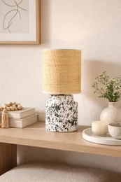 Modern black and white table lamp with rattan shade, featuring a speckled ceramic base.