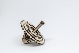 A silver-colored spinning top toy with intricate gear-like patterns and a central metal rod.