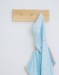 Wooden coat rack with blue patterned towel hanging on it. Wooden chair in the background.
The product is a COAT RACK LENNY, which is a kids room accessory. It is made of wood and has a simple, minimalist design. The image shows a blue patterned towel hanging on the coat rack, indicating that it can be used to hang various items such as towels, clothes, or accessories. The wooden chair in the background complements the overall style of the room decor.