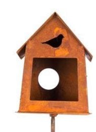 Small rustic bird house on a stick with a silhouette of a bird on the front. Made of weathered orange-brown wood.