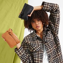 Black clutch bag with a textured houndstooth pattern, featuring a zipper closure and a wrist strap for easy carrying.