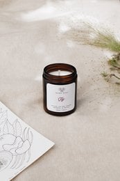 A round, tall glass candle jar with a dark brown label featuring the text "Fig Candle". The candle is made of natural wax and has a wooden wick.
