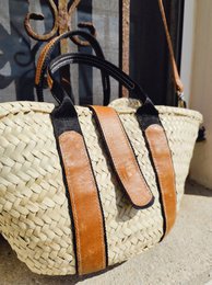  Straw tote bag with double bicolor handles and magnetic closure. Features a woven design with contrasting orange and black accents.