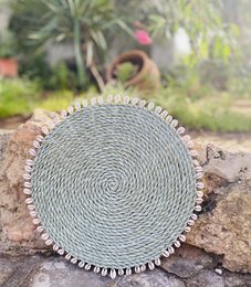Round woven placemat in light green color with decorative tassels around the edge.