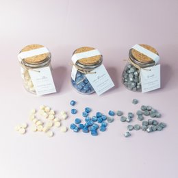  Glass jars containing assorted wax beads in various colors including white, blue, and gray. The jars are labeled as part of a "Winter Collection" and are described as "Sealing Wax Beads" that can be used for envelope seals and hobbies/stationery.