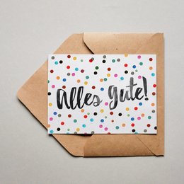 Colorful polka dot greeting card with the text "Alles Gute!" (German for "All the best!"). The card is in a square format and has a brown envelope.