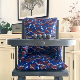 Colorful patterned cushion for a baby high chair, featuring a vibrant blue and red abstract design.