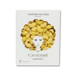 Cavatappi pasta in a bronze color with a stylized face design. The pasta is shaped into a circular pattern resembling a hairstyle.