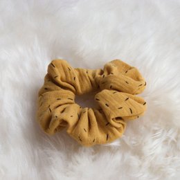 Mustard yellow scrunchie with polka dot pattern, made of soft, stretchy fabric.