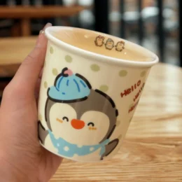 Ceramic mug with a cute penguin design, perfect for Christmas gifts.