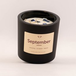 Gemstone scented candle in the September fragrance, featuring a round, tall glass container with a black label.