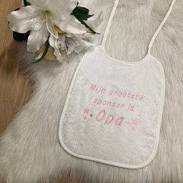 "Soft, white baby bib with the text 'Mijn grootste sponsor is Opa' (My biggest sponsor is Grandpa) printed on it. The bib has a simple, minimalist design with stars around the text."
This baby bib has a soft, white fabric material. The text "Mijn grootste sponsor is Opa" (My biggest sponsor is Grandpa) is printed on the bib in a simple, minimalist style with stars surrounding the text. The design and text on the bib suggest it is intended as a gift or keepsake for a grandparent.