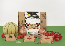 A round, tall candle with a rustic, natural design featuring various fruits and vegetables. The candle is packaged in a wooden box with a label that says "Breizh who can!".