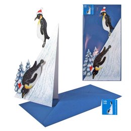 A 3D folding card featuring penguins on a snowy mountain scene. The card has a whimsical, winter-themed design with penguins sliding down the mountain slopes.