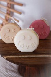  Decorative pillar candles in various pastel colors with the word "Love" embossed on the surface. The candles have a simple, round shape and appear to be made of wax.