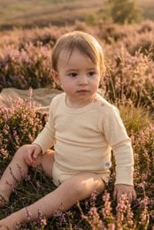 Soft, natural-colored merino wool baby romper with long sleeves. Suitable for newborns and infants.