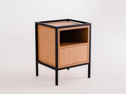 A tall, rectangular bookcase with a single drawer and open shelving. The bookcase has a wooden frame in a light natural finish, with a black metal frame. The bookcase appears to be a simple, minimalist design suitable for storing books and other items.