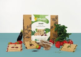 A small plant growing kit containing soil, seeds, and gardening tools in a compact cardboard box.