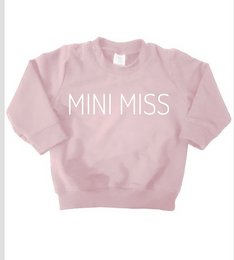 A pink sweater for baby girls, featuring the text "MINI MISS" in white. The sweater is available in sizes 56 to 104/110.