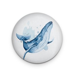 A decorative round magnet featuring a whimsical illustration of a jumping whale in shades of blue.
