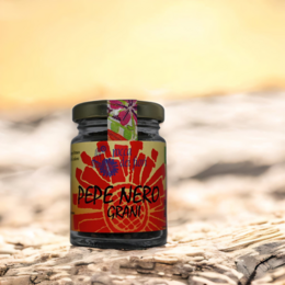 Organic black pepper grains in a glass jar with a vibrant, colorful label featuring the text "Pepe Nero" and a decorative design.