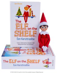 A plush elf figure in a red suit, holding a book titled "The Elf on the Shelf - Een kersttraditie" (The Elf on the Shelf - A Christmas Tradition). The elf is standing next to a Christmas tree and other holiday decorations.